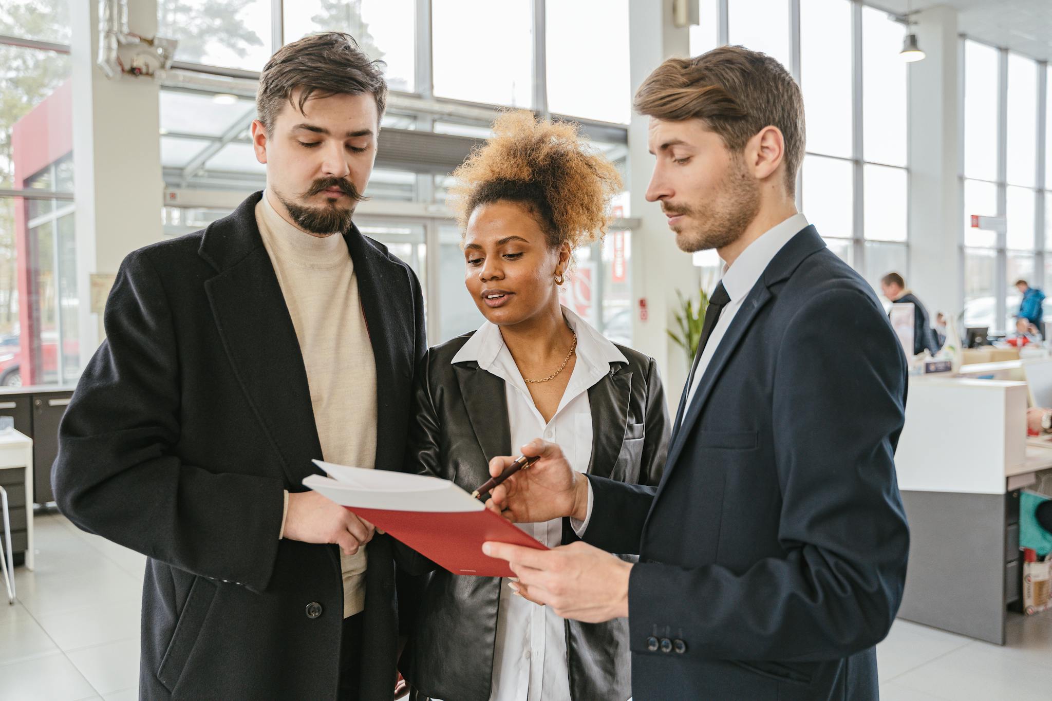 Three professionals discussing and reviewing documents in a modern office space.